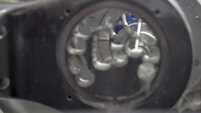 Macro video recording of a dental milling machine working process. Hi-speed spindle with water cooling is carving on a titanium disc. Water splashing and dripping around.