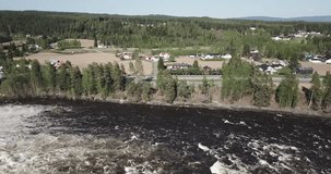 Drone shot of waterfall by a power plant in the summer sun. The flood is at the highest in the river. No colorgrading or editing done to the video.