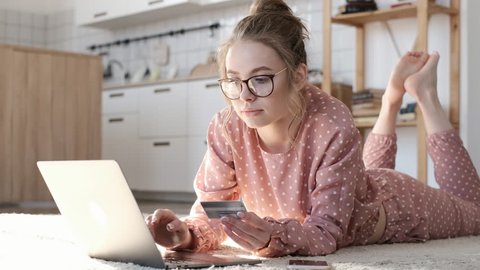 Female hand holding credit card and shopping online. Easy pay using digital gadget. Girl using laptop at home. Happy woman with compact computer and bank card shopping online. Lifestyle.