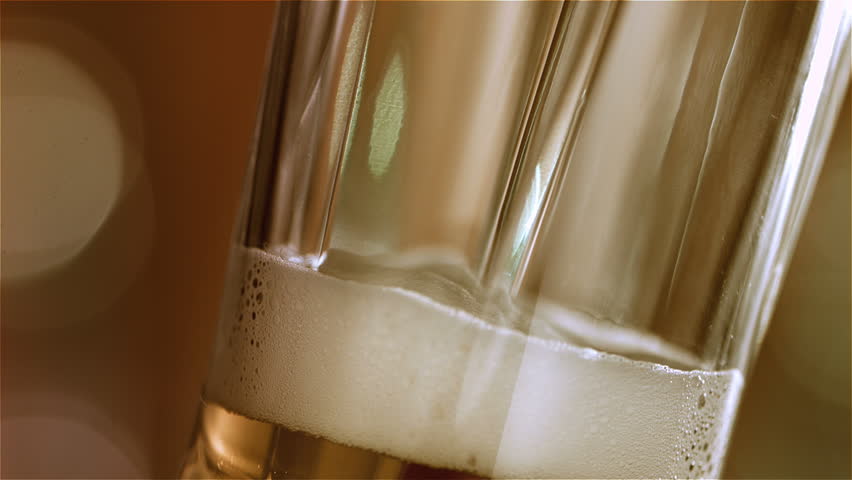 Beer is pouring into angled glass. IPA on tap. Cold Light Beer in a glass with water drops. Craft Beer forming waves close up. Freshness and froth. Bar background. Microbrewery craft beer. | Shutterstock HD Video #1025849786
