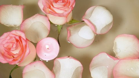 pink roses with petals and burning candles floating in water bowl, spa concept, wedding concept