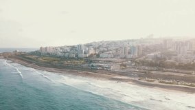 Aerial view of coast in Haifa. Urban top view with azure ocean rippling waves 4K
