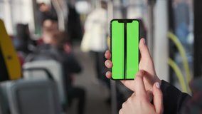 Lviv, Ukraine - May 19, 2018: Close up woman hands use touch holding a mobile telephone with a vertical green screen in tram chroma key smartphone technology cell phone street message slow motion