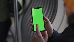 Lviv, Ukraine - May 19, 2018: Slow motion woman hands use touch holding a mobile telephone with a horizontal green screen in tram chroma key smartphone technology cell phone street touch message