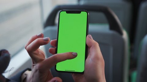 Lviv, Ukraine - May 19, 2018: Closeup of a woman's hand holding a mobile telephone with a vertical green screen in tram chroma key smartphone technology cell phone street touch message display hand