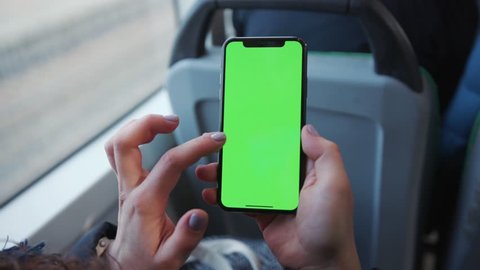 Lviv, Ukraine - May 19, 2018: Slow motion woman's hand holding a mobile telephone with a vertical green screen in tram chroma key smartphone technology cell phone street touch message display hand