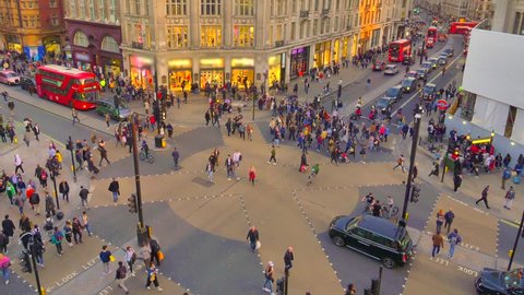 Evening time lapse of Oxford circus and regent street junction with rush hour traffic of both pedestrians, cars and Red double deck buses.