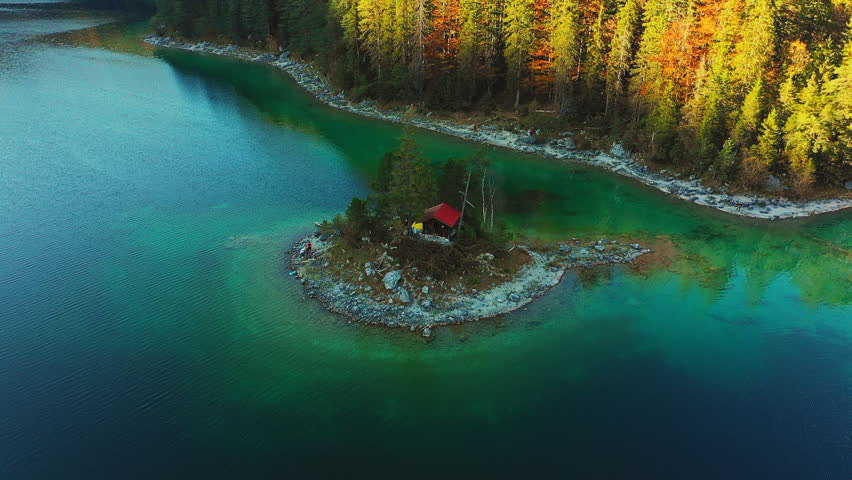 Overhead aerial shot of a cabin sitting on top of a small islet.
