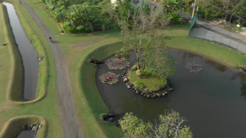 Beautiful outdoor park view with small lake and man riding motorbike aerial footage