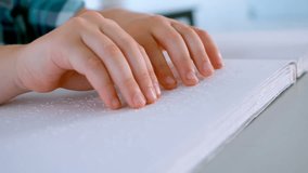 Close-up of blind Caucasian schoolboy hands reading a braille book at desk in classroom at school. He is touching and feeling 4k - Powered by Shutterstock - Get 15% off with code: PIKWIZARD15