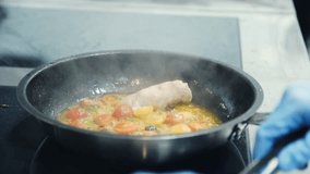 Someone frying fish and vegetables in a frying pan. The chef is preparing a fish dish. Fish dish. Seafood. Food video close up slow motion.