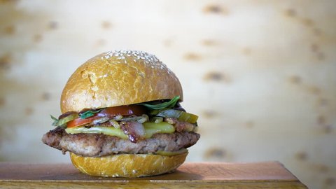 Rotating of fresh-cooked tasty burger on a wooden board, close up