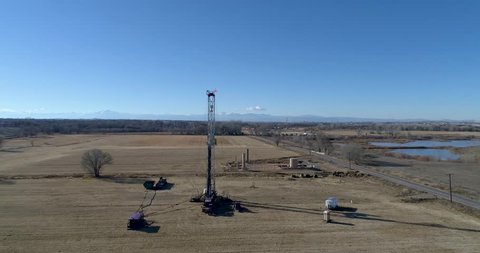 Greeley, Colorado / United States - 01 13 2019: Fracking well head orbit #2 with rocky mountains and ponds in background.