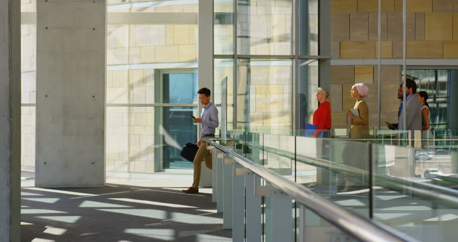Side view of a group of diverse business people walking through the corridor to attend to the business seminar in office building.