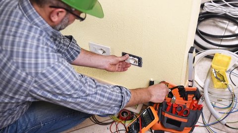 Electrician technician worker with the screwdriver engaged to repair an electric socket in a residential electrical system. Construction industry. Building. Footage. 