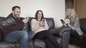 Group of young adults sitting on couch using their smart phones