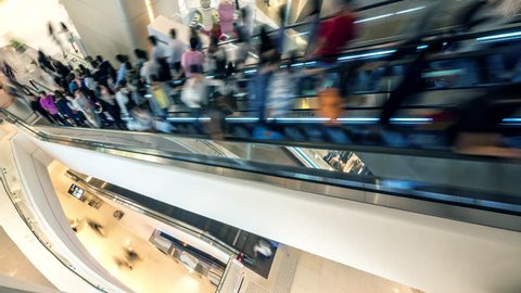 Abstract blurred scene of moving people on escalator in shopping mall in Asia