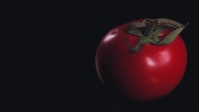 Close shot of a large red tomato. Tomato spinning on dark in slow motion. On a black background lies a tomato. Red Tomato. Food performance. Food video. 