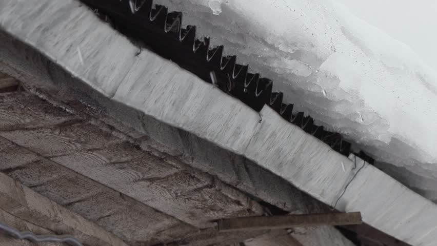 snow melts and water drops drip from the old roof of the house