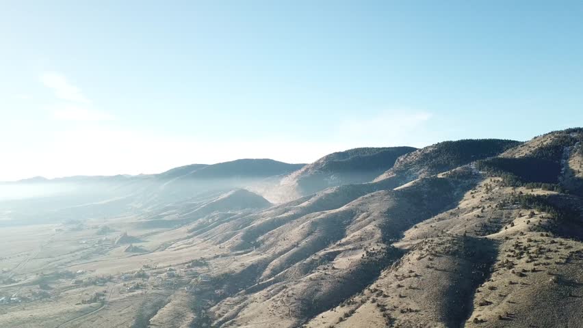 AERIAL: extreme wide pull away over the mountainous terrain containing the giant boulders located at the Red Rocks Park in Colorado.