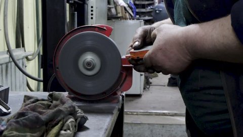 worker grinds a brake pad on a grinding machine