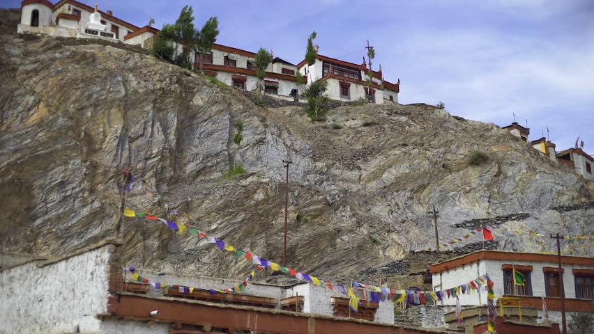 Several old buildings on the top and bottom of a cliff in a mountainous region of India