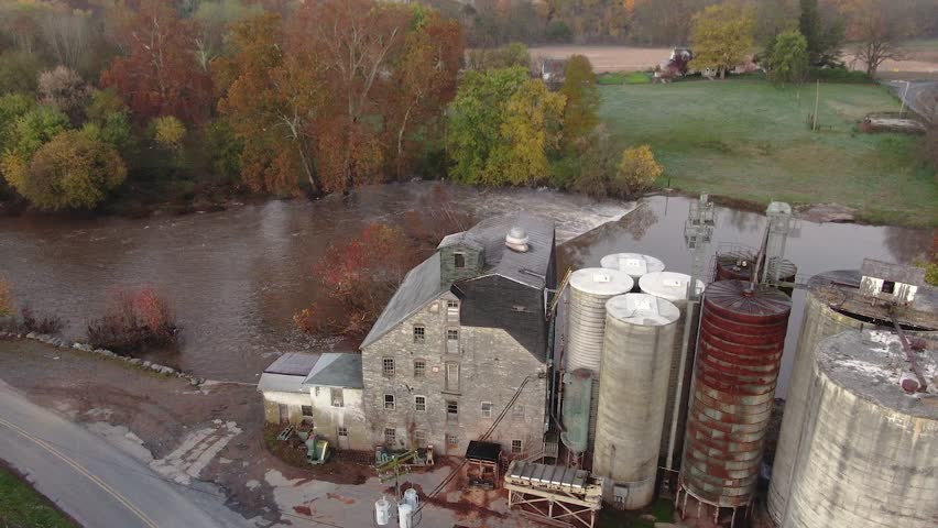 Old dam landmark blocks river current in autumn, drone jib ascends