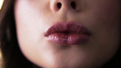 Extremely close up footage makeup artist making final touch with brush on lips young woman. Process application lip gloss to makeup model. Sensual pursing. Front view