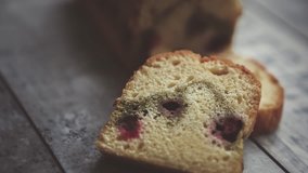 Footage of delicious sponge cake with cherry cut into pieces on wooden table.Tasty home baked biscuit dessert in close up.Enjoy natural pastry product for coffee break or lunch