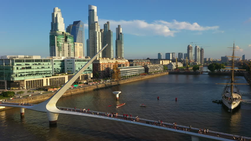 Aerial drone view of Puerto Madero harbor with Puente de la Mujer bridge and skyscraper buildings in the background. Buenos Aires, Argentina.