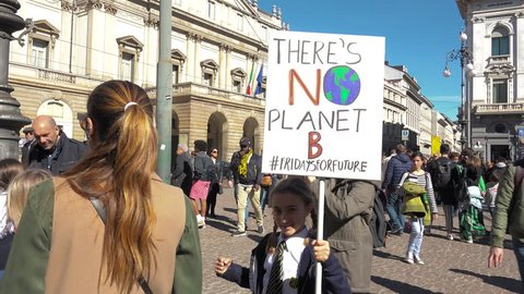 MILAN, ITALY - MARCH 15, 2019: Happy little girl demonstrating at global strike for climate. Beautiful student with picket sign "THERE'S NO PLANET B", new generation smiling child at Friday for future