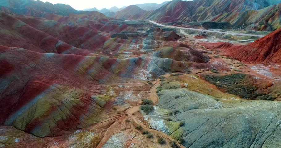 Aerial 4k drone shot of most colorful landscape on earth, the rainbow mountains of Zhangye Danxia National Geological Park. Flying above multicolored slopes covered by striped pattern.  Royalty-Free Stock Footage #1025962898