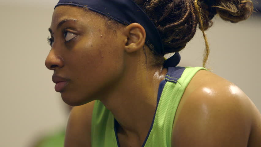 A female basketball player listens to coach give a pep talk at half time in the locker room