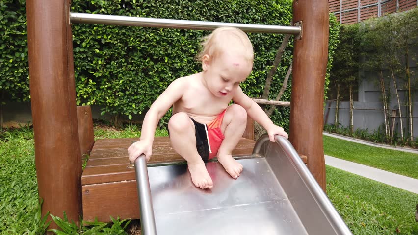 two-year-old blond boy with great joy and fun down the hill on the Playground.
