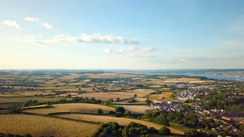 Flying Over Sunny UK Countryside with Houses and Ocean in the distance - 4K Aerial Footage