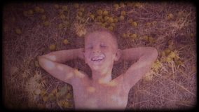 Family video archive. Retro camera 8 mm. Vintage. A little boy lies under a big tree among small apples. Unstoppable children's laughter. Happy childhood. Childhood dreams. Journey back to childhood