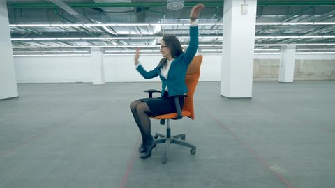 Businesswoman riding a chair, having fun at the office.