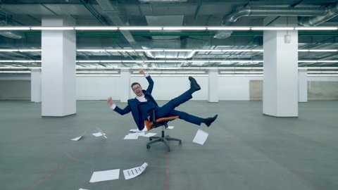 Happy office worker throws paper in the air while sitting in a chair.