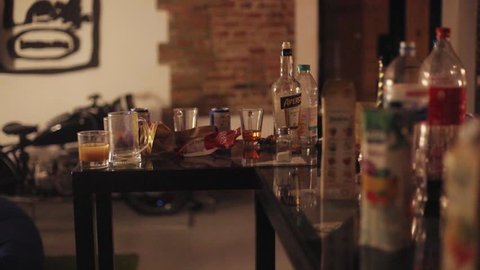 Tokio, Japan - April 7, 2018: Close up view of empty alcoholic bottles and glasses on the messy crammed table in a cozy loft designed flat. No people around. Partying, hanging out with friends