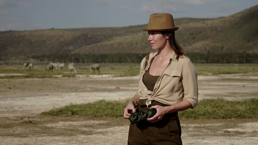 Woman spottings wild animals at savanna in Kenya