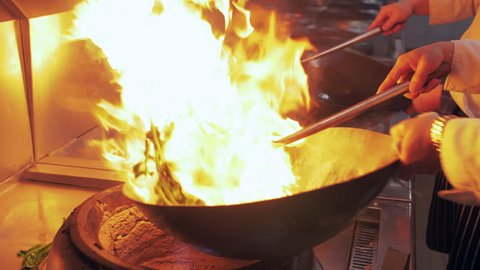 Slow motion of Chef Cooking in the Kitchen, Restaurant wok fire cooking Close up, cook frying vegetable in the commercial kitchen. Chinese style Sichuan food cooking 4k clip