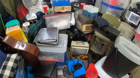 Cluttered object filled room.  Slow dolly out over piles of household items, vintage electronics, business equipment and miscellaneous junk.
