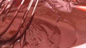 Melted dark chocolate. Mixing melted chocolate with a whisk. Liquid of hot chocolate. Confectionery. Confectioner prepares dessert.