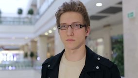 Portrait of a modern young man in glasses and leather jacket in a large modern shopping center. Shopping.
