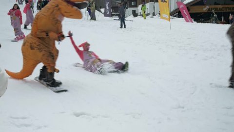 Rosa Khutor, Russia - 03.16.19: Boogel Woggel festival - T-rex dinosaur down the slope on a snowboard