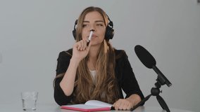 Young blond woman Records a podcast, lecture, or webinar on a dictaphone. Woman in headphones speaks into the microphone at the table

