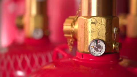 Close up of fire suppression gas cylinder valves and pressure gauge.