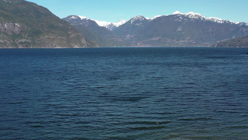 Aerial view over Burrard Inlet, ocean and island with mountains in beautiful British Columbia. Canada. 4K.