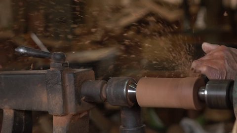 Slow motion of worker turning wood on a lathe