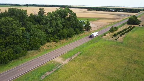 RV travels down empty country road in rural Kansas, Aerial tracking shot 4k